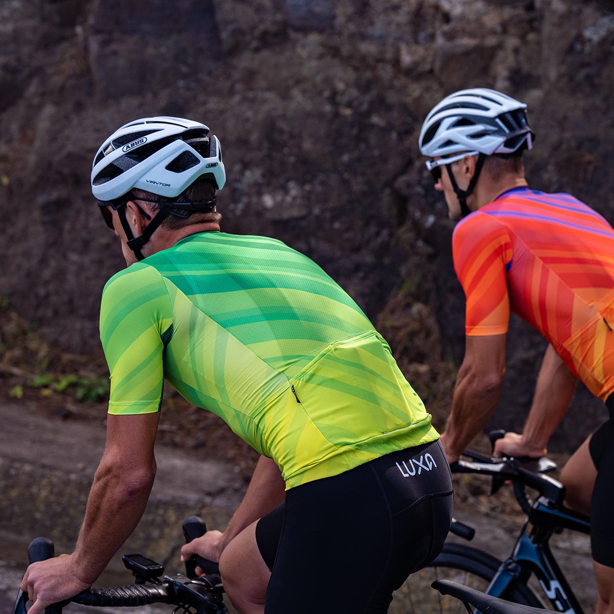 Zwei Radfahrer in hellorangefarbenen Luxa-Radbekleidungen